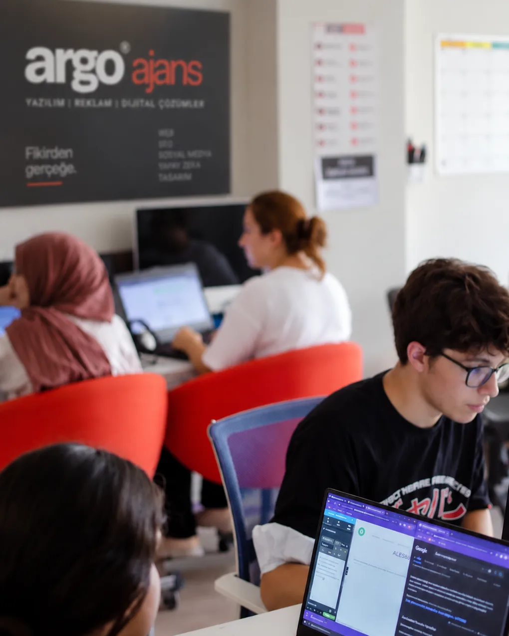 Argo Ajans’ın İzmir Alsancak’taki stüdyosu: Argo Ajans duvar logosunun altında masalarında çalışan ekip